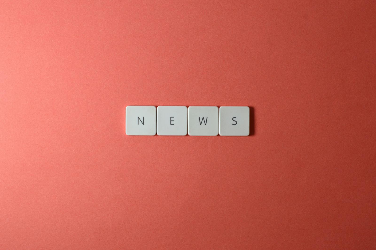 Close-up of keyboard keys spelling 'NEWS' on a red background, minimalist style.