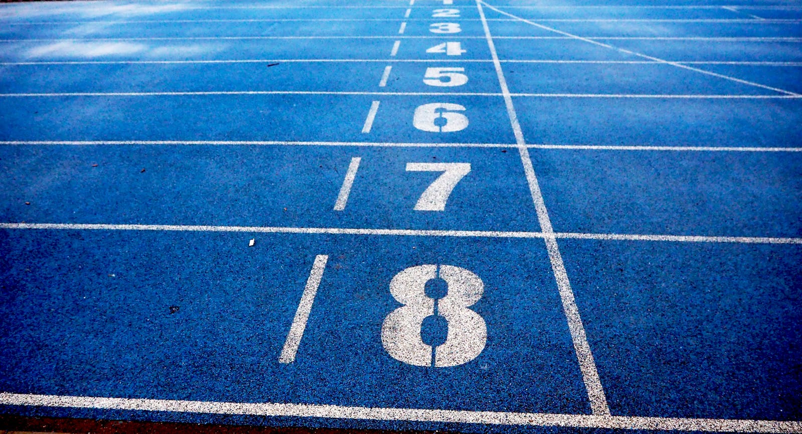 Blue athletic running track with numbered lanes, ideal for sports events and race preparations.